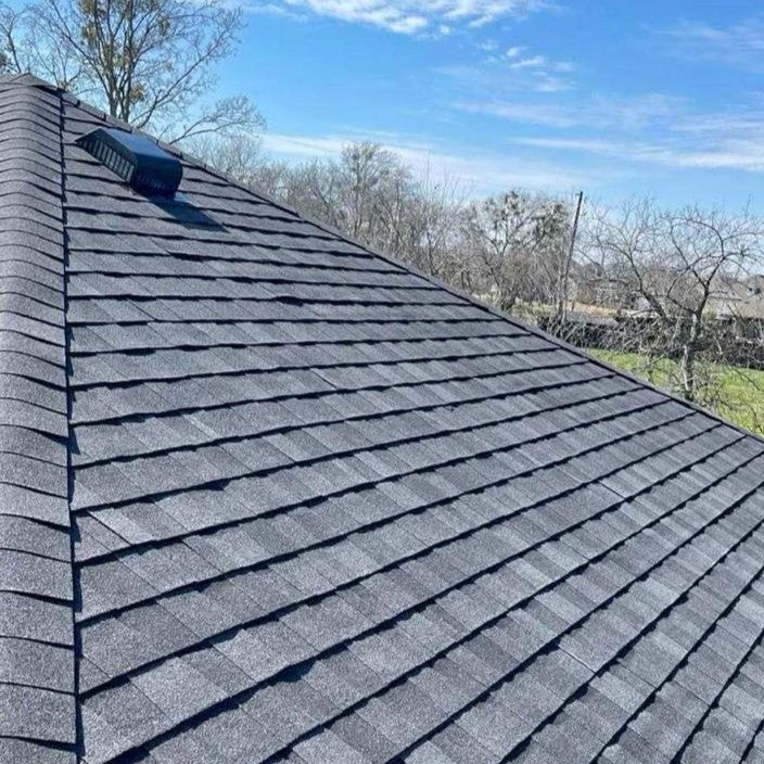 Roof with gray shingles under a clear blue sky